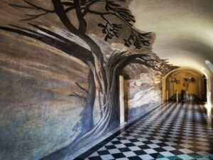 L'anamorfosi in uno dei corridoi del convento. Di scorcio si osserva la raffigurazione di san Francesco di Paola in preghiera sotto un albero.